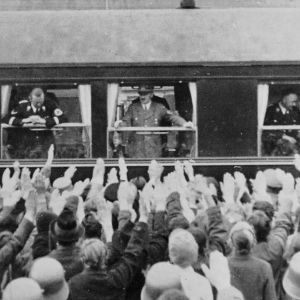 1938,Hitler auf der Durchfahrt mit Station in Wörgl, neben Adolf Hitler sieht man offenbar auch den Chef des Reichssicherheitshauptamtes, Obergruppenführer Reinhard Heydrich (links) aus dem Fenster schauen, und durch das offene Fenster rechts ist Reichsführer Heinrich Himmler im Gespräch mit Offizieren zu erkennen 
